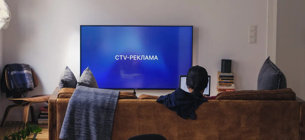 Жінка на дивані дивиться Smart TV з написом «CTV-реклама» на екрані