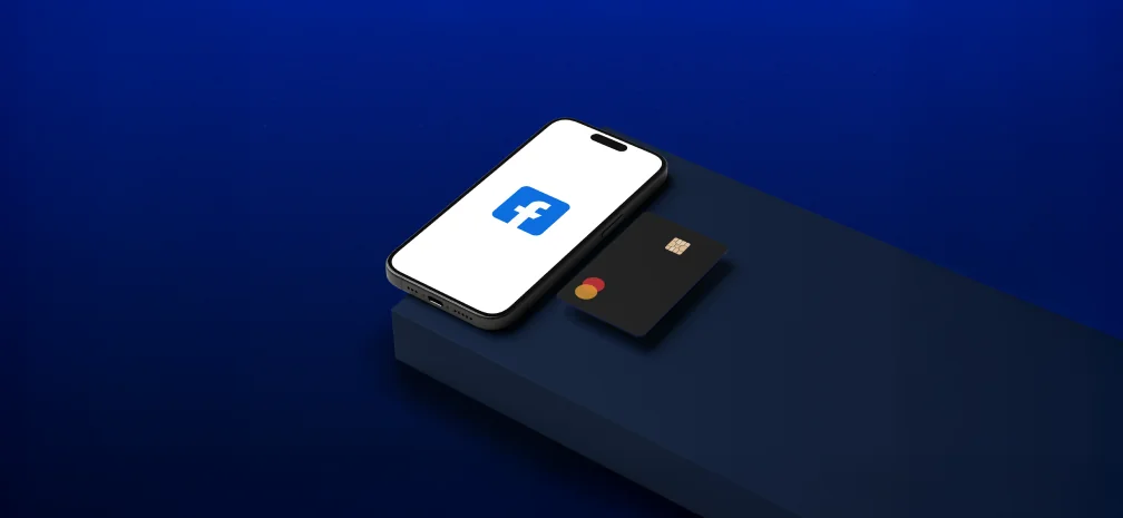 Смартфон із логотипом Facebook та банківська картка на темному фоні